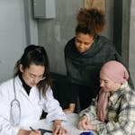 A female doctor consults two patients at a desk in a medical clinic, emphasizing diversity and professionalism.